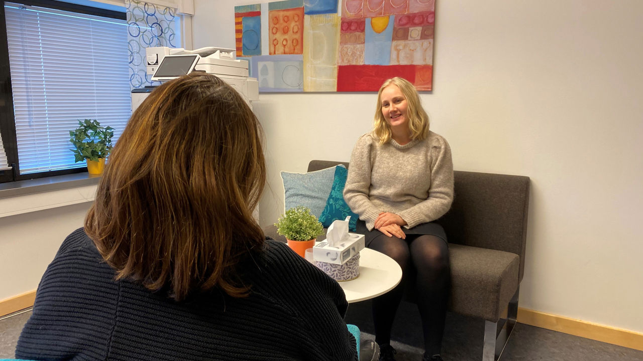Helsesjukepleiar sit i samtale med ein elev