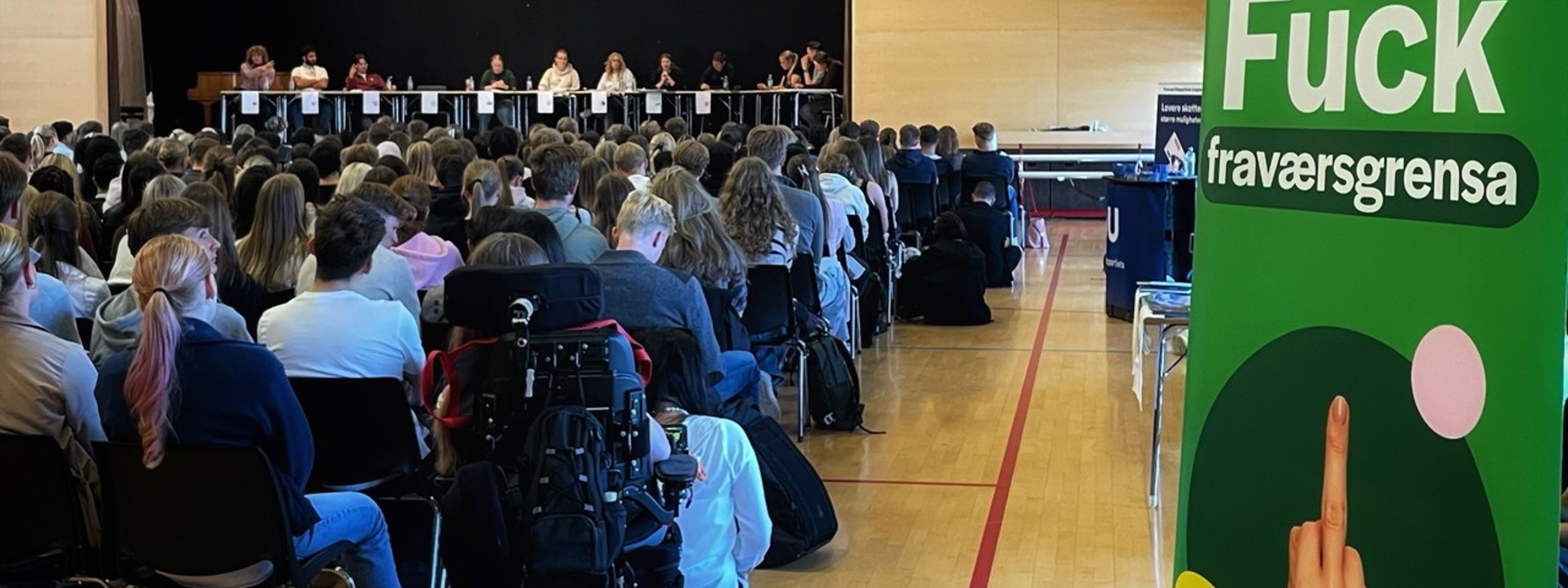 Representantar for kvart ungdomsparti sit på ei scene framfor sittande ungdom i ein gymsal