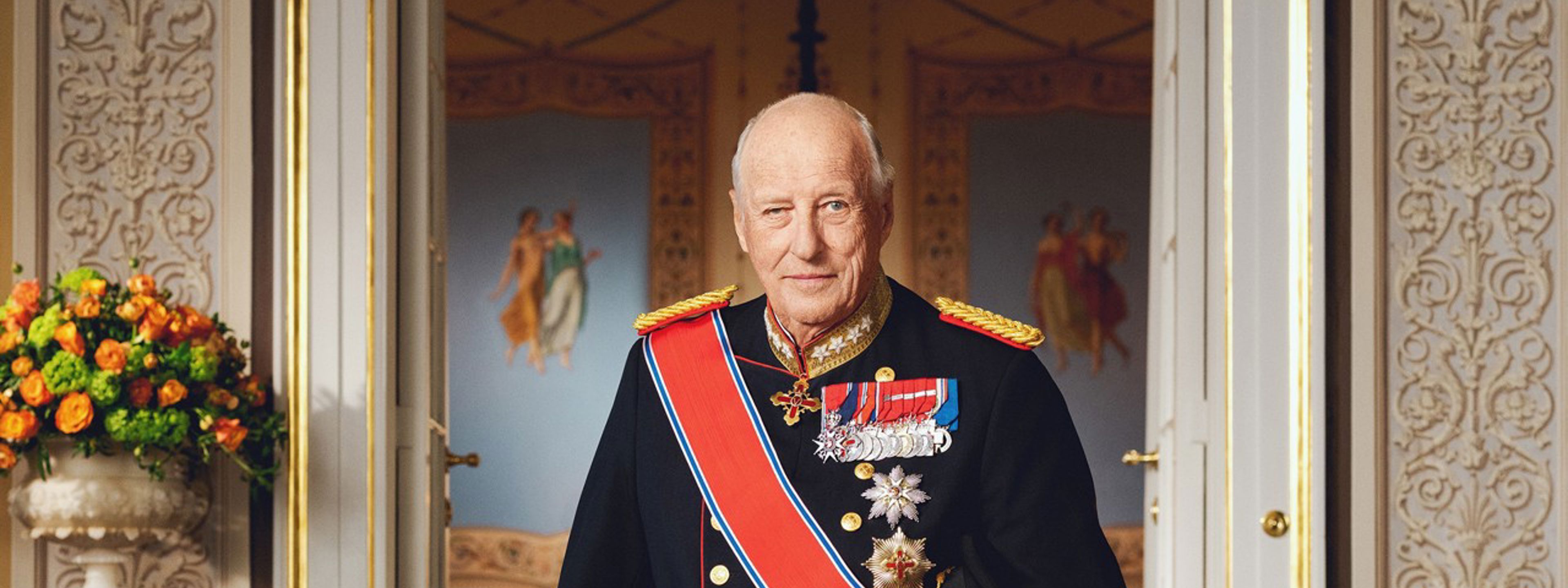Kong Harald V står i gallauniform inne på slottet