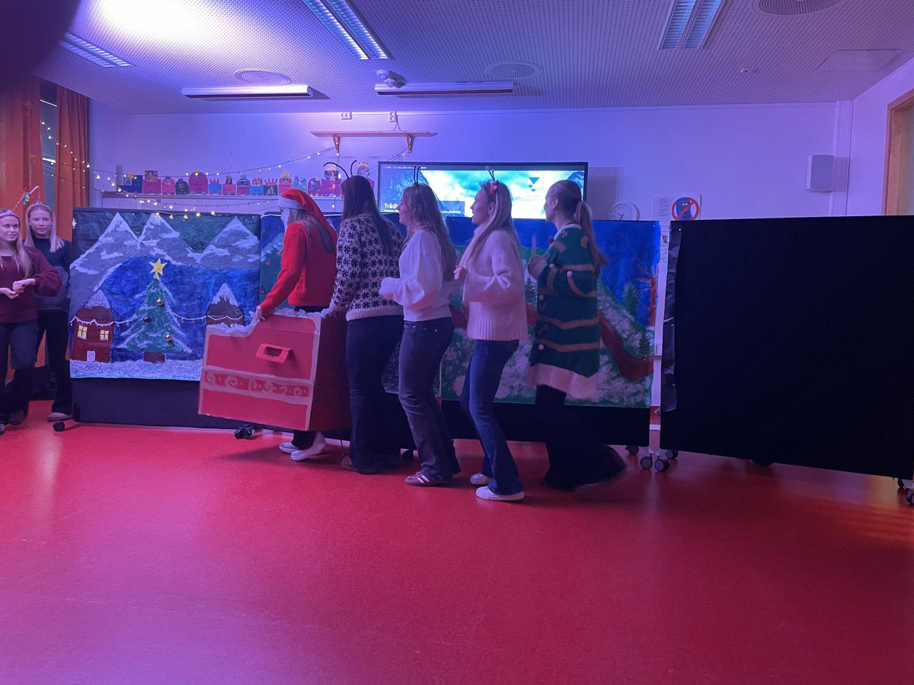 Elevar som dansar framfor malte hus på ei tavle