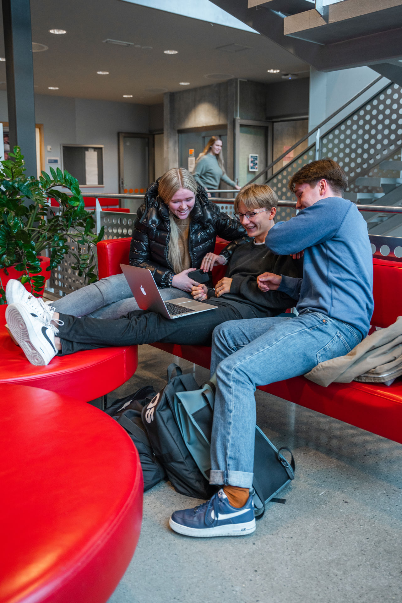 Elevar sit i ein raud sofa og ser på ein pc