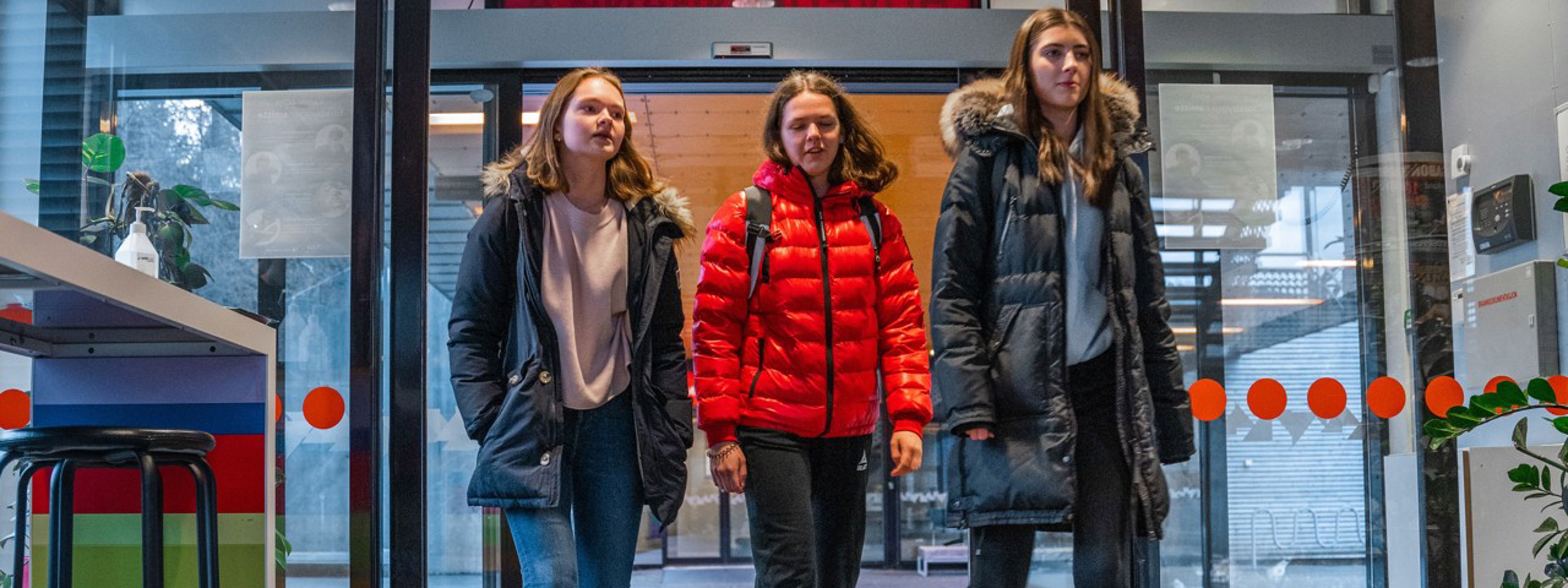 Tre jenter går inn hoved døra på skulen